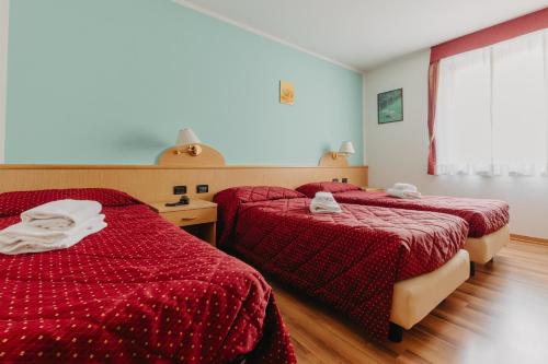 a hotel room with two beds with red sheets at Hotel Spera in Strigno