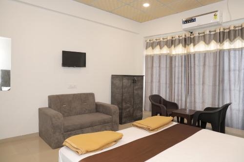a room with a bed and a chair and a television at Hotel Sky Blue in Surat