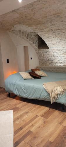 a bedroom with a bed with a stone wall at A l'ombre des sentiers in Cuisiat