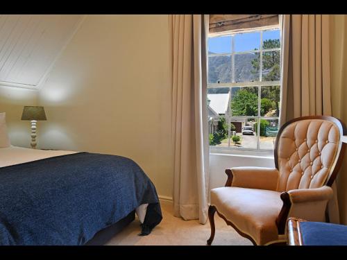 a bedroom with a bed and a chair and a window at Sunflower Villa in Franschhoek in Franschhoek