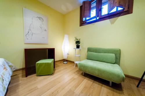 a living room with a green chair and a window at Villa Don Juan II in Segovia