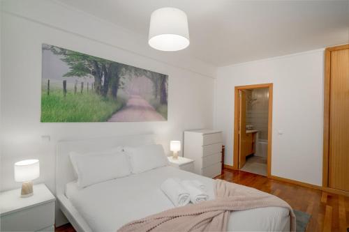 a bedroom with a white bed with a painting on the wall at Sea Side Cozy Matosinhos in Matosinhos