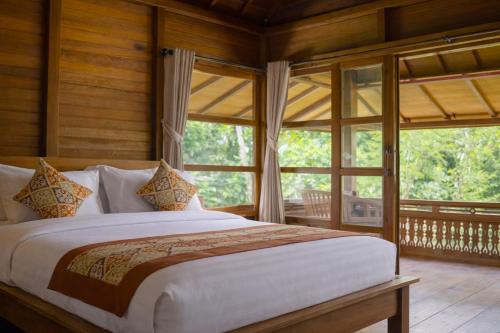 a bedroom with a large bed in front of a window at Alam Bulangan Villa in Sukawati