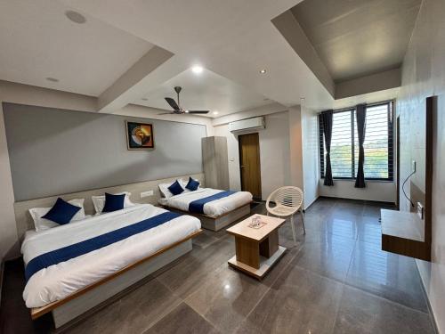 a hotel room with two beds and a table at Hotel Jb Classic in Himatnagar