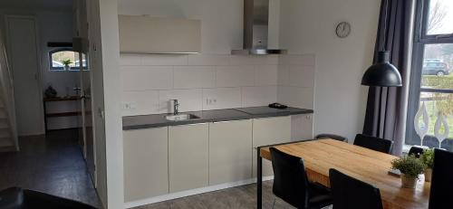 a kitchen with a sink and a table with chairs at Antares-Ameland in Hollum