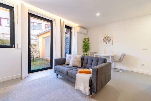 a living room with a couch and large windows at Bonfim Charming Flats by HostWise in Porto