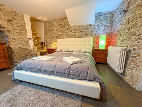 a bedroom with a large bed and a stone wall at B&B - Studio Arcodia in San Marco dʼAlunzio