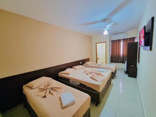 a room with three beds and a ceiling at Portal Palace Hotel in Aparecida