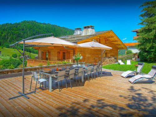 a wooden deck with chairs and tables and umbrellas at Chalet Le Mousqueton - OVO Network in La Clusaz