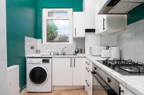 a white kitchen with a washer and dryer in it at Exotic 4BD, Etihad, Coop Arena - TV in all Rooms and Outdoor Dining in Manchester