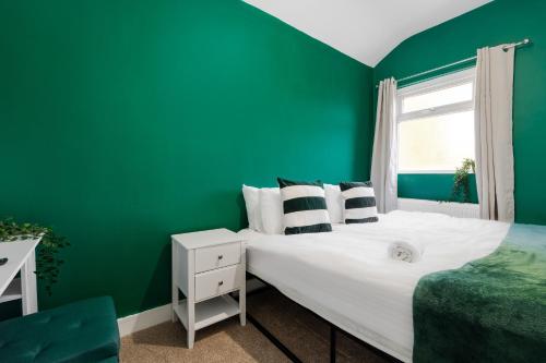 a green bedroom with a bed and a window at Exotic 4BD, Etihad, Coop Arena - TV in all Rooms and Outdoor Dining in Manchester