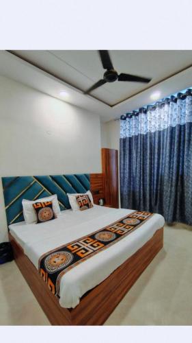 a bedroom with a large bed with blue curtains at Aastha view inn in Amritsar