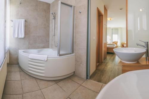a bathroom with a large tub and a sink at Rosi's Dorfwirtschaft in Rottenacker