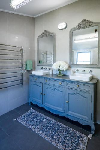 a blue bathroom with two sinks and a mirror at Rosewood Terrace in Bathurst