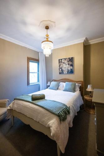 a bedroom with a large bed and a chandelier at Rosewood Terrace in Bathurst
