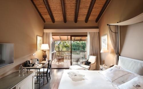 a bedroom with a bed and a desk and a balcony at Asia Gardens Hotel & Thai Spa, a Royal Hideaway Hotel in Finestrat