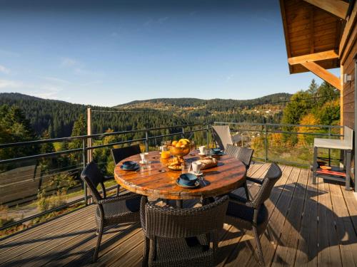 a wooden table with chairs on a deck with a view at Chalet L'Ursus - OVO Network in Gérardmer