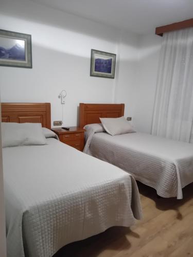 two beds in a hotel room with white sheets at El Ancla Ponferrada in Ponferrada