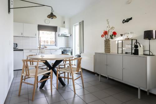 a kitchen with white cabinets and a table and chairs at Zilt vakantiehuisje - Rekerlanden 283 in Schoorldam
