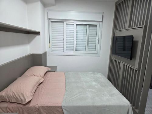 a small bedroom with a bed and a window at LOFT1304 Maxplaza Canoas in Canoas