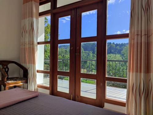 a bedroom with a large glass door with a view at New Wasala Guest in Diyatalawa