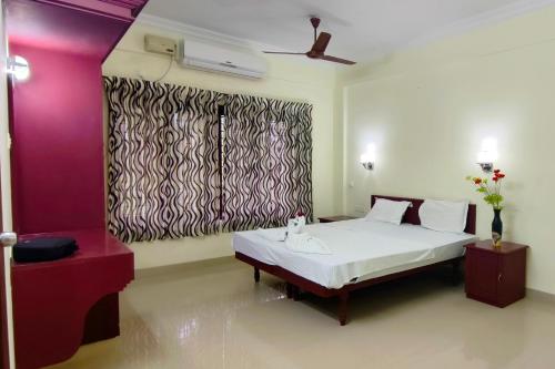 a bedroom with a white bed and a window at Dew Drops Inn kovalam in Kovalam