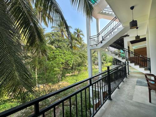 a balcony of a house with a staircase and palm trees at Kumarana in Bentota