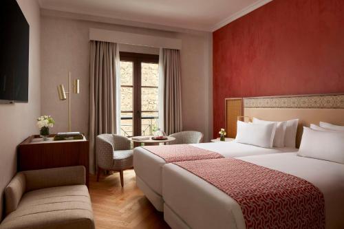 a hotel room with a large bed and a table at NH Collection Palacio de Córdoba in Córdoba