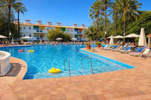 a large swimming pool with chairs and a hotel at Palma Rima Hotel in Kololi