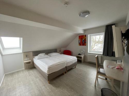 a bedroom with a bed and a desk and window at Hotel & Restaurant Friedrichshöhe in Braunschweig