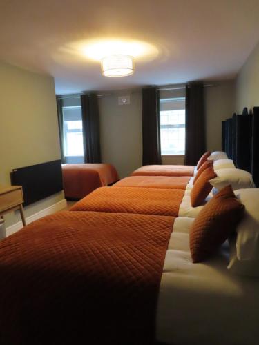 a hotel room with two beds with orange sheets at The Stable Loft at Troysgate in Kilkenny
