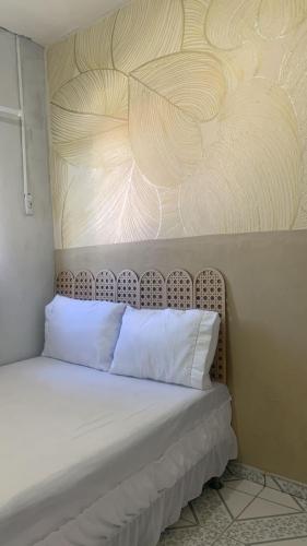 a bed with white pillows in a room at Quarto Recando do Sol in Aracaju