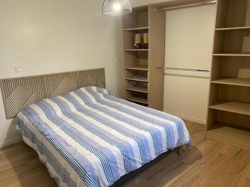 a bedroom with a bed and a closet with shelves at Appartement Le Pellerin 2ch et 2sdb in Le Pellerin