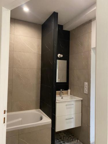 a bathroom with a bath tub and a sink and a bath tubermott at Appartement Le Pellerin 2ch et 2sdb in Le Pellerin