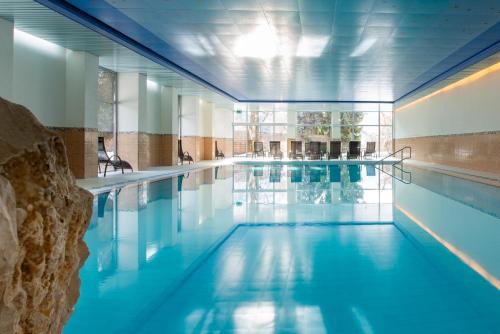 a swimming pool with blue water in a building at Badehotel Salina Maris – Wellness & Vintage in Mörel