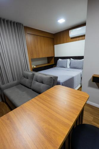 a room with a bed and a couch and a table at Flat exclusivo Studio Cuiabá 1211 in Cuiabá
