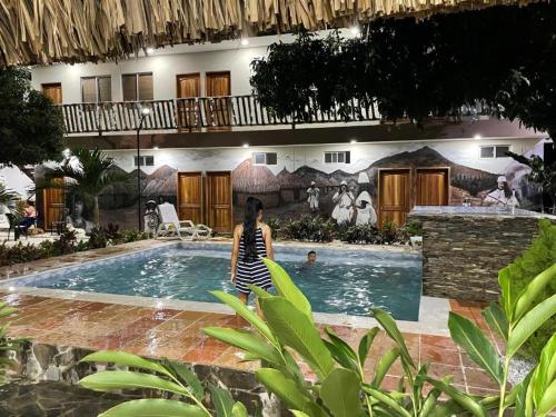 a woman sitting in front of a swimming pool at Hostal Los Arhuacos in Santa Marta