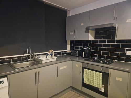 a kitchen with white cabinets and a sink and a stove at Happy Lodge Gillingam Kent in Gillingham