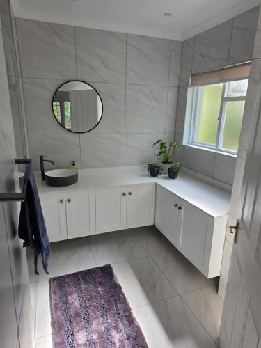 a white bathroom with a sink and a mirror at Jonker's Cottage in Malgas