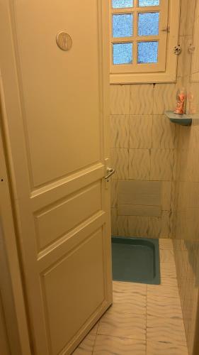 a door to a bathroom with a shower and a window at La chambre dorée avec jardin privé in Dar Salah Bey