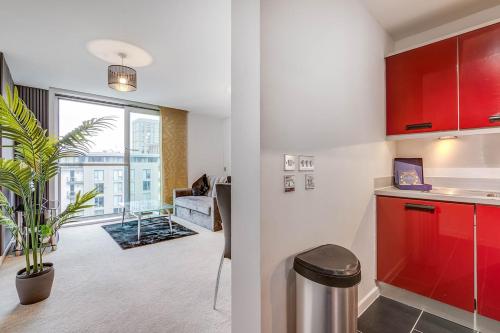 a kitchen with red cabinets and a living room at Ruby City Stay Apartment CMK Free Parking in Milton Keynes