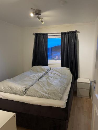 a bed in a room with a window at Sentrumsnær sokkelleilighet in Svolvær