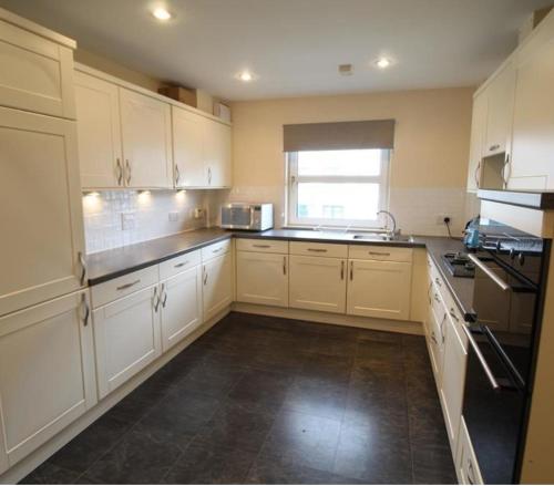 a large kitchen with white cabinets and a window at Grandholm Crescent in Aberdeen