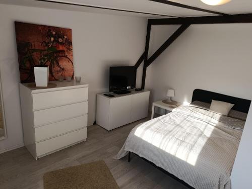 a bedroom with a white bed and a tv at Apartament Mariacka in Bydgoszcz
