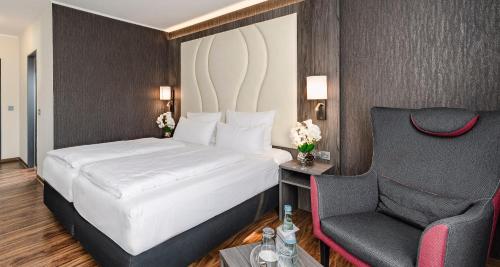 a bedroom with a large bed and a chair at PLAZA INN Grevenbroich in Grevenbroich