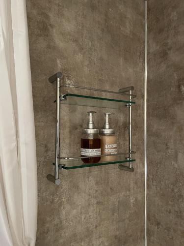 a metal shelf with two bottles on a wall at Craigruie Farmhouse in Balquhidder
