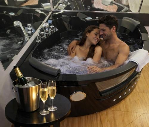 a man and a woman in a hot tub with wine glasses at Smart Hotel in Carpi