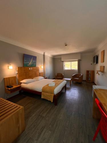a hotel room with a large bed and a chair at Le Saint Georges Hotel in Port Louis