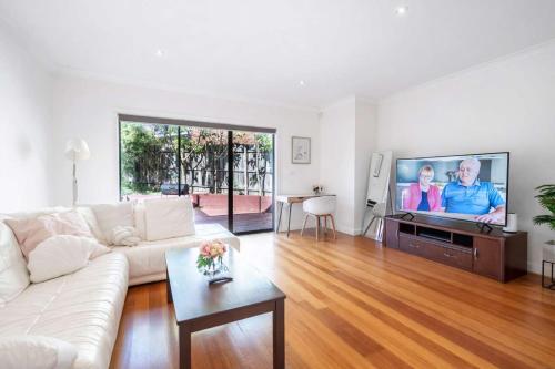 a living room with a white couch and a flat screen tv at Welcome home Burwood in Burwood