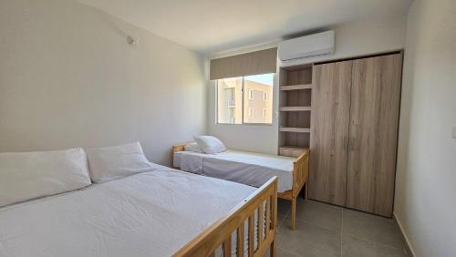a small bedroom with two beds and a window at Capriella, Serena Del Mar in Cartagena de Indias